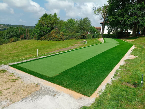 Augusta Outdoor tee line consisting of one continuous green synthetic grass strip surrounded by trees